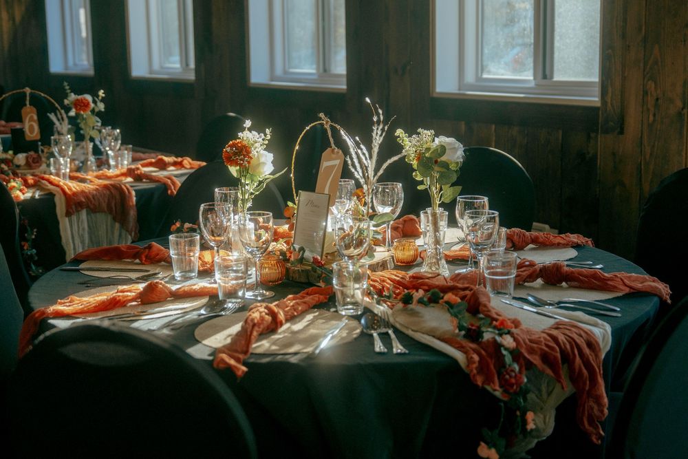 Elegant wedding reception tables set with burgundy accents and glassware.