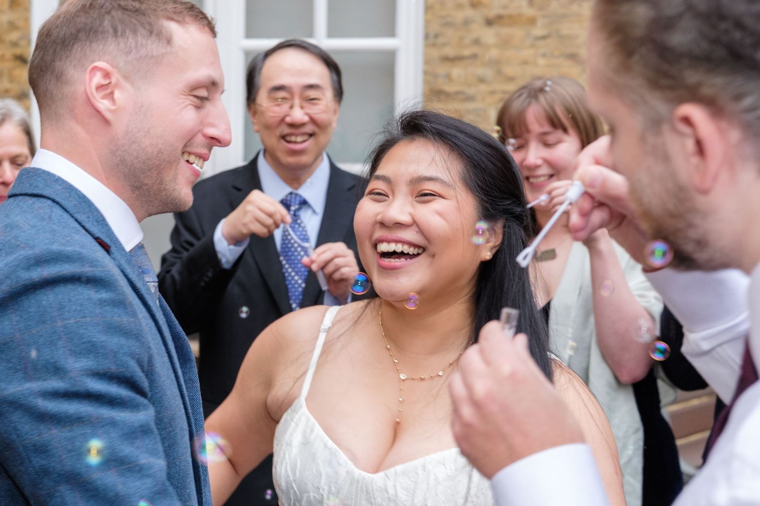 Wedding guests share joyful laughter and candid moments during outdoor reception celebration.