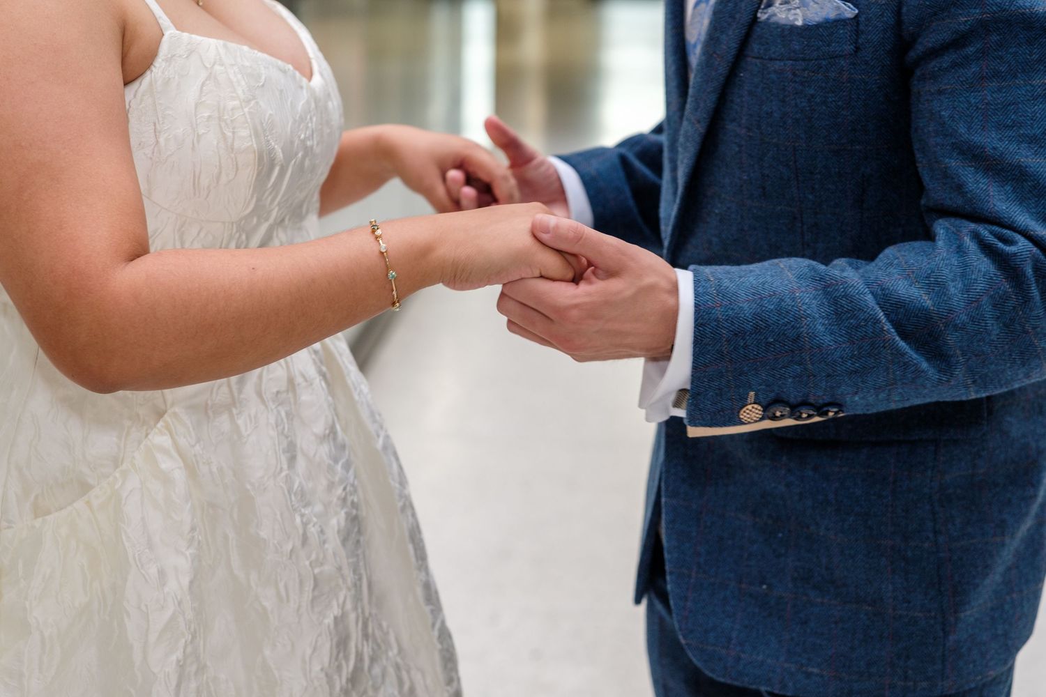 A couple exchanges rings during an intimate wedding ceremony in formal attire.