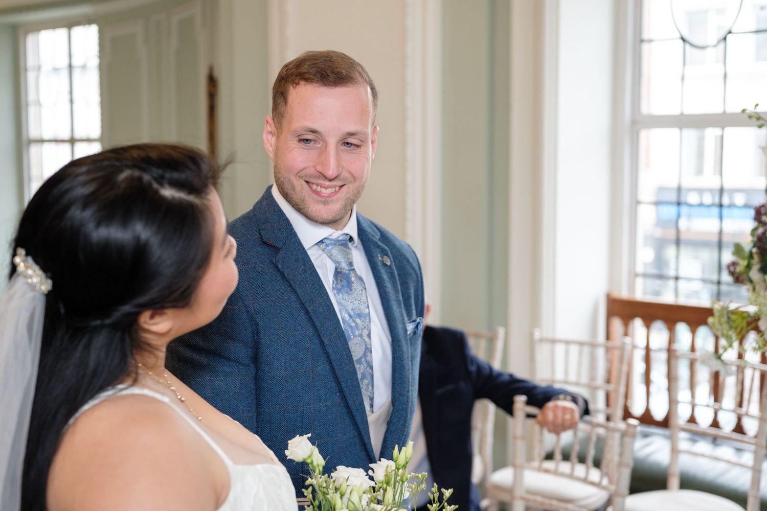 A joyful moment shared between a couple during their wedding ceremony in a bright interior space.