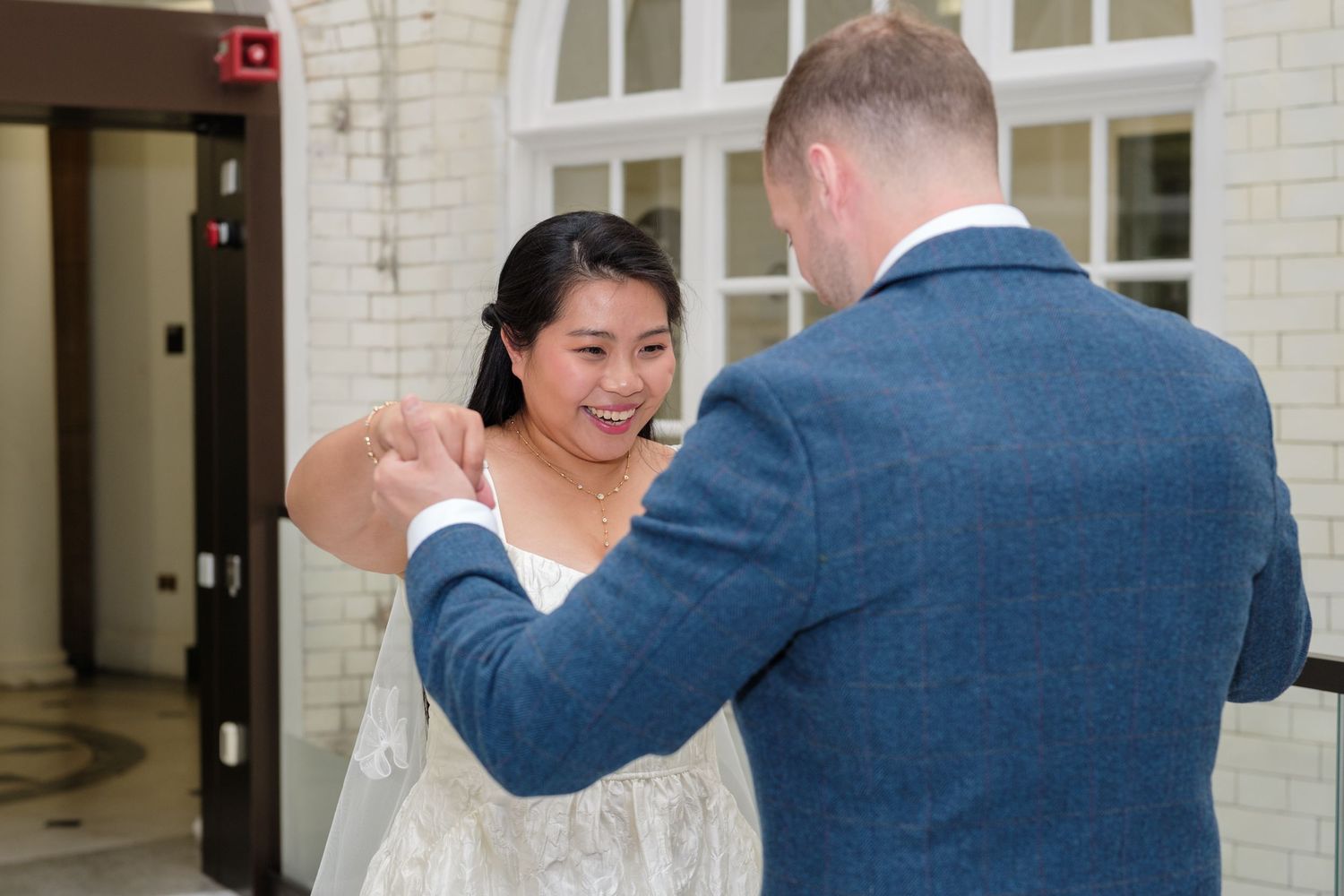 A couple shares their first dance together at their wedding, with the bride in white and groom in navy blue.