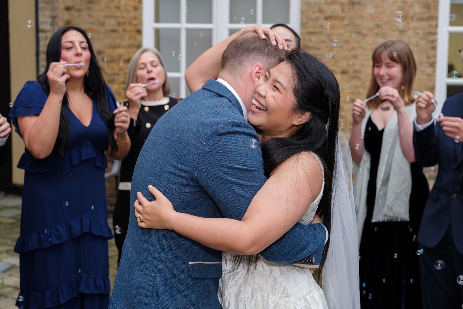 Joyful guests celebrate at a wedding reception with dancing and embracing in navy blue attire.
