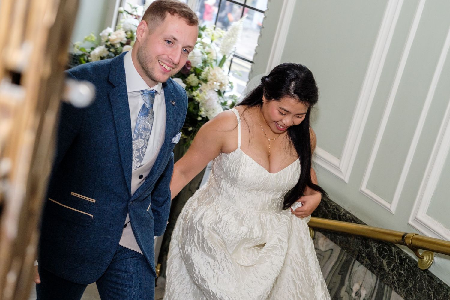 A couple shares a romantic dance together in an elegant indoor venue with white decor.