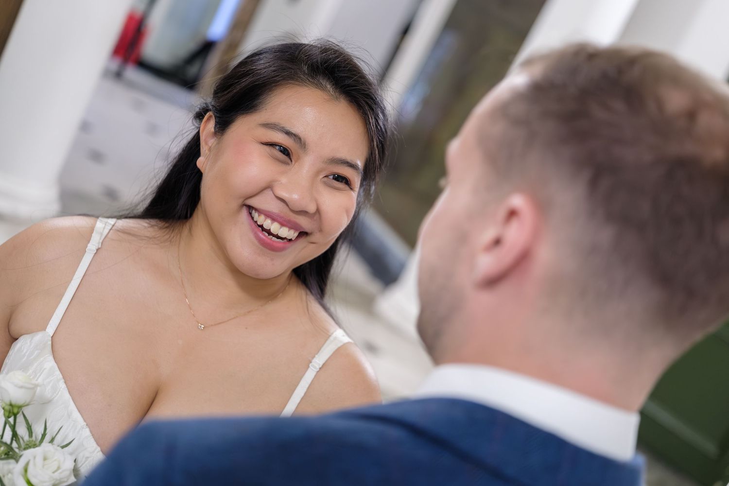 A bride and groom share joyful laughter during their outdoor wedding ceremony.