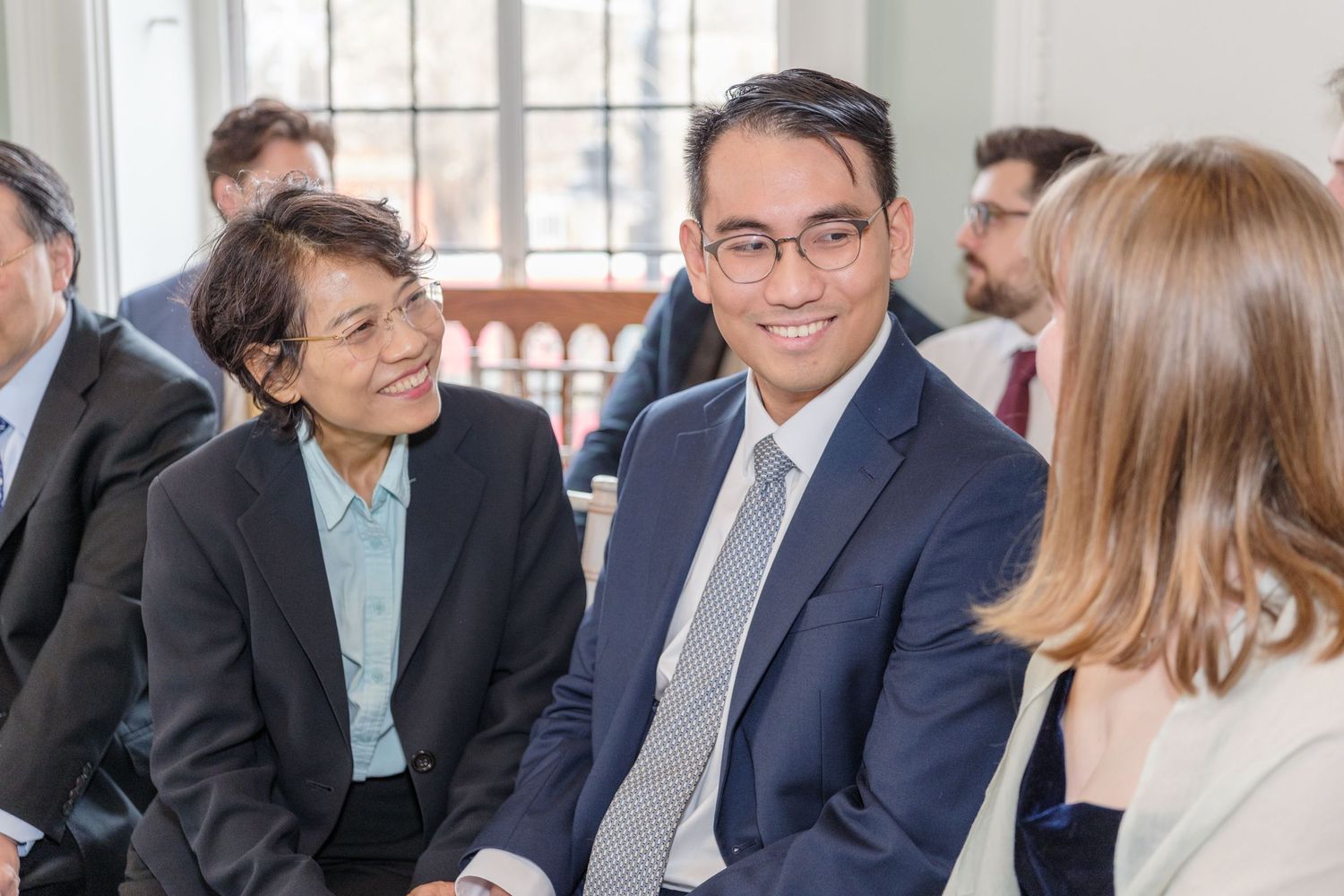 Business professionals engage in animated conversation during a networking event in a bright office setting.