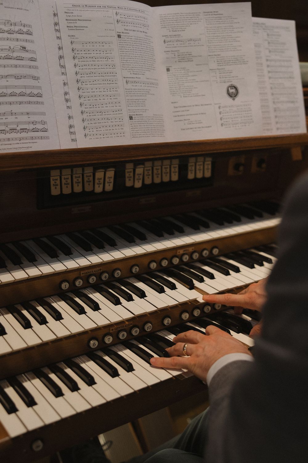 Sheet music and hands playing piano keys during a wedding performance.