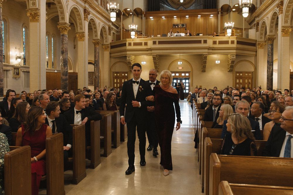 Panoramic view of a traditional church interior with wooden pews filled with people during a wedding ceremony.