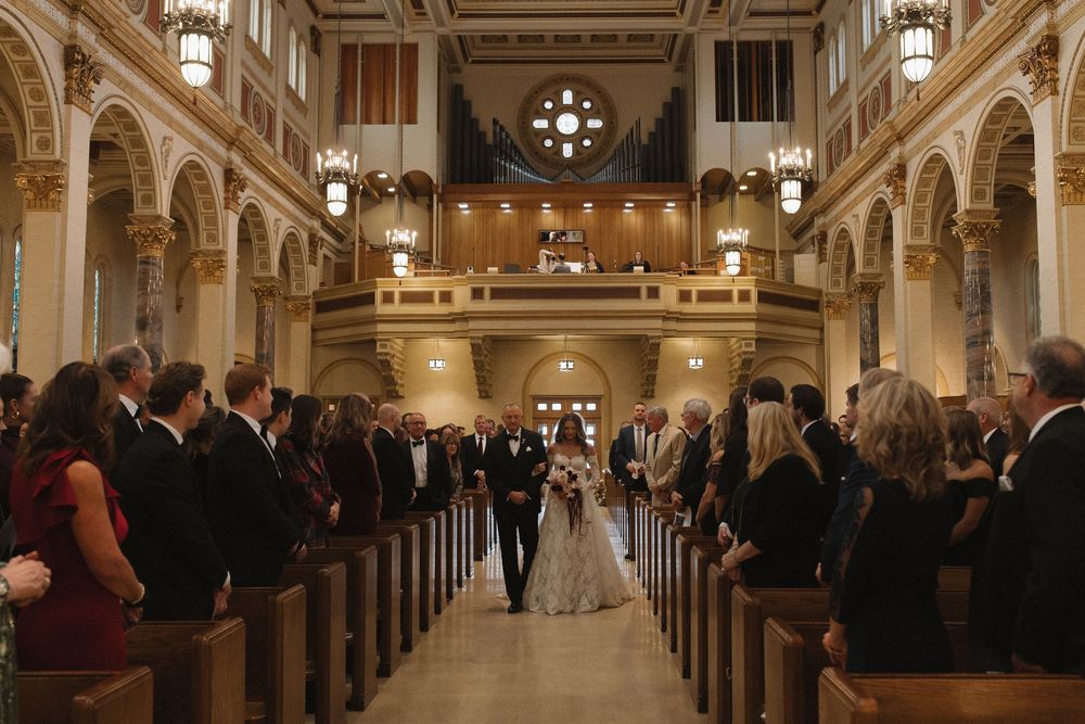 Wedding ceremony in a grand cathedral with ornate architecture and glowing chandeliers illuminating the aisle.