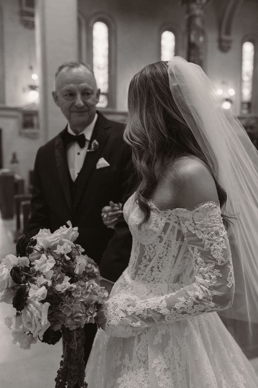 A close-up of an elegant lace wedding dress with floral bouquet.