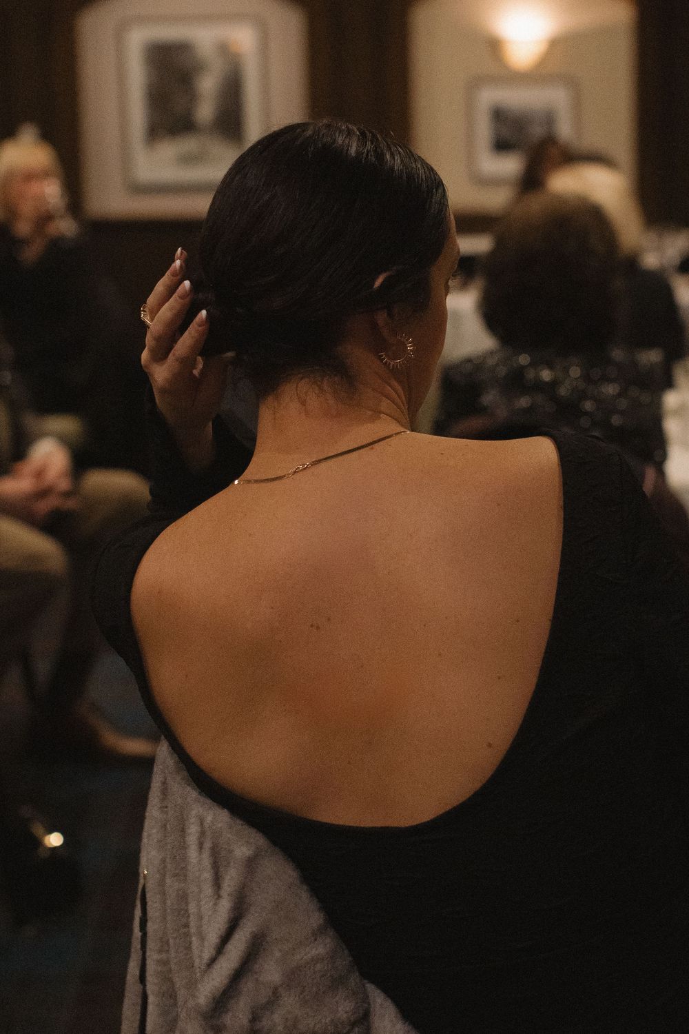 Close-up view of a woman's bare shoulders and back in an elegant evening setting.
