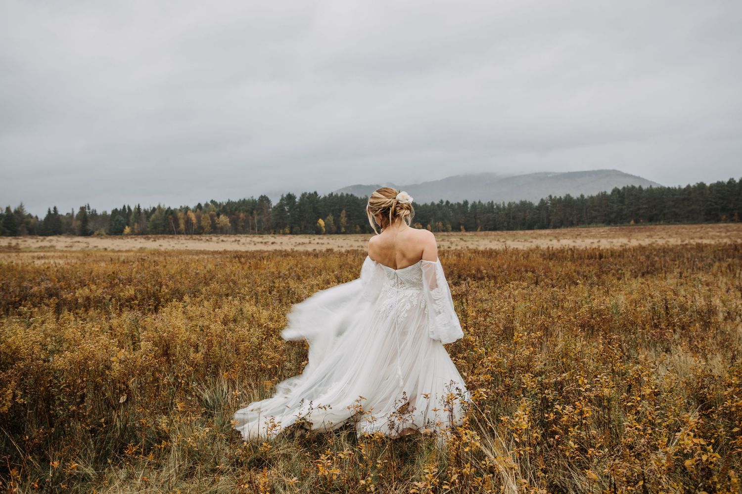bride running through a field with the adirondack mountains in the background