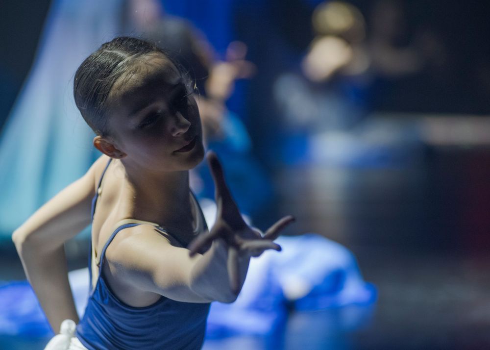 Contemporary dancers perform expressive movements in dramatic blue lighting during a stage performance.