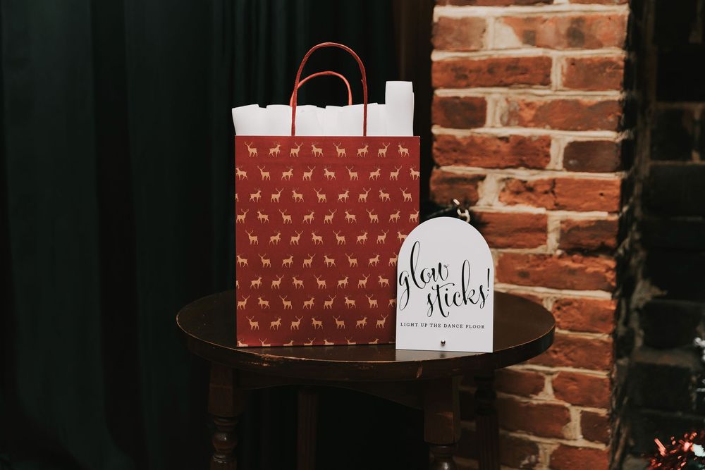A row of brown paper shopping bags with handles sit against a rustic brick wall.