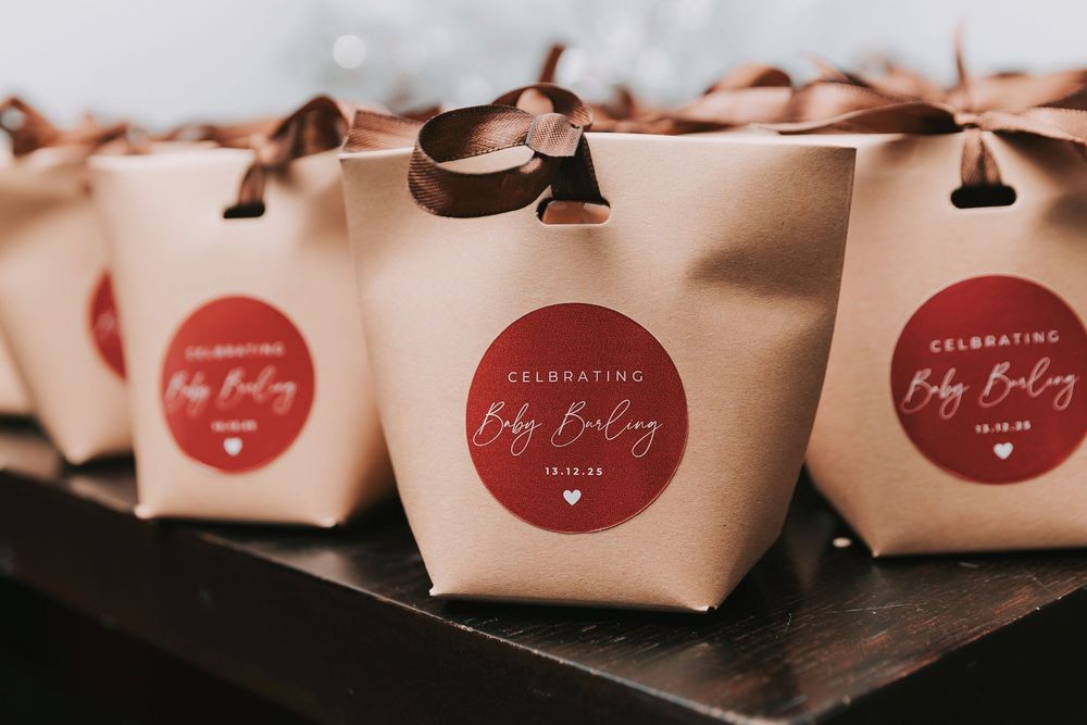Small gift boxes wrapped in blush pink paper with red circular stickers lined up in a row.