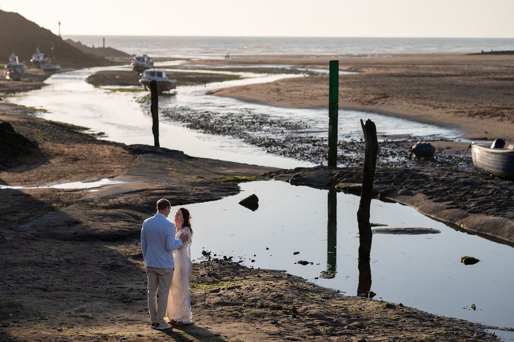 Just married couple on the beach in Bude, photographed in soft light by the water