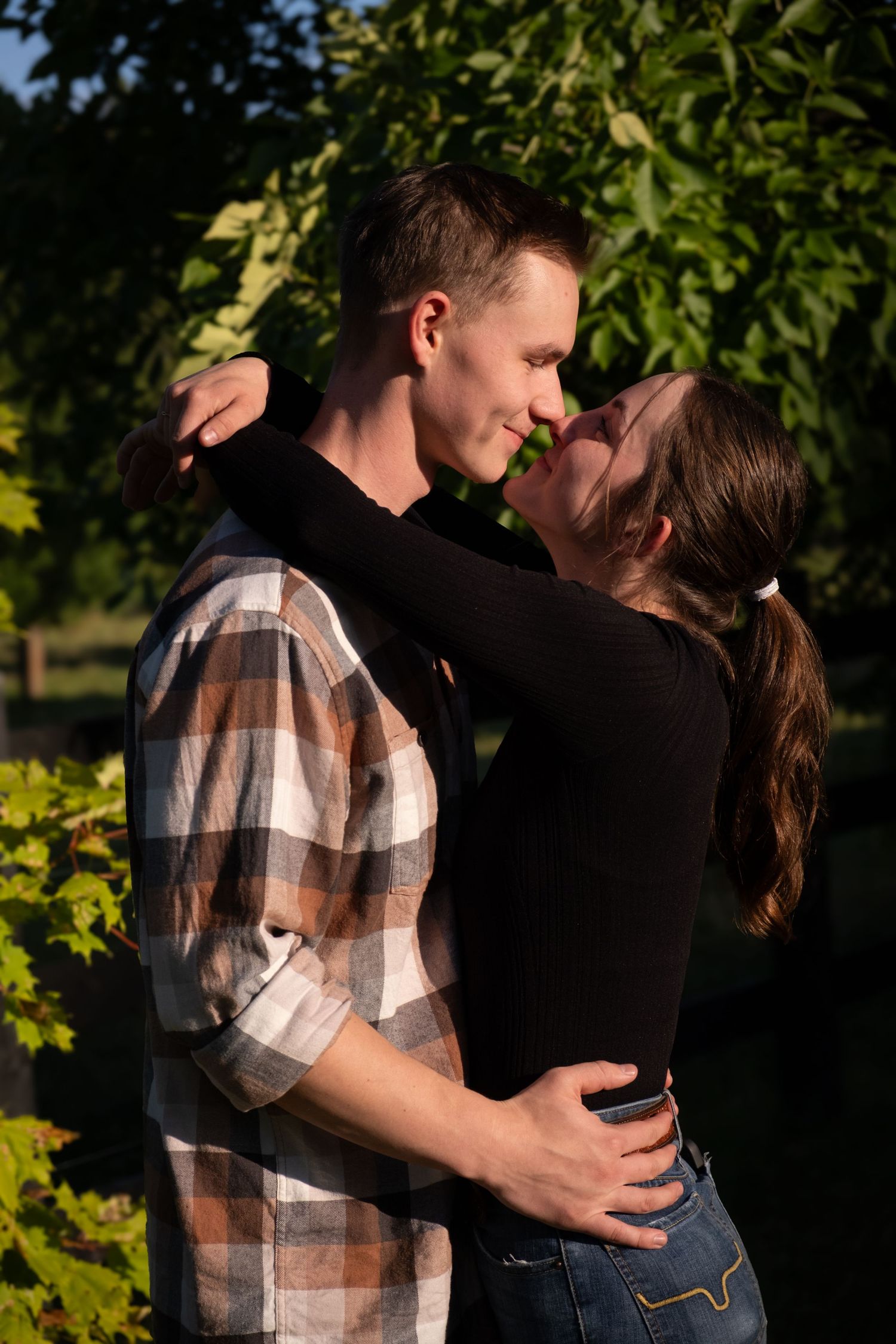 Romantic sunset moment between couple in park with plaid shirt and black top.