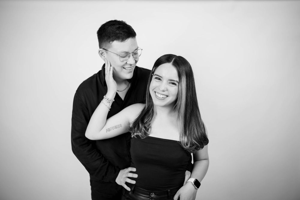 A playful black and white studio portrait of a couple sharing a joyful moment.