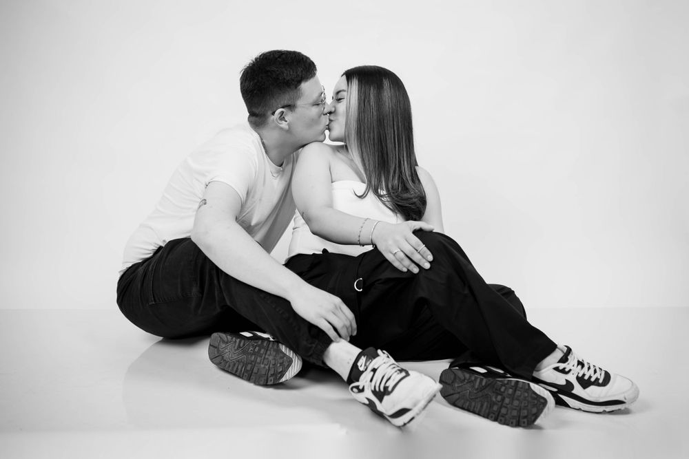 Intimate black and white photo of a couple sitting close together on the floor in casual wear.