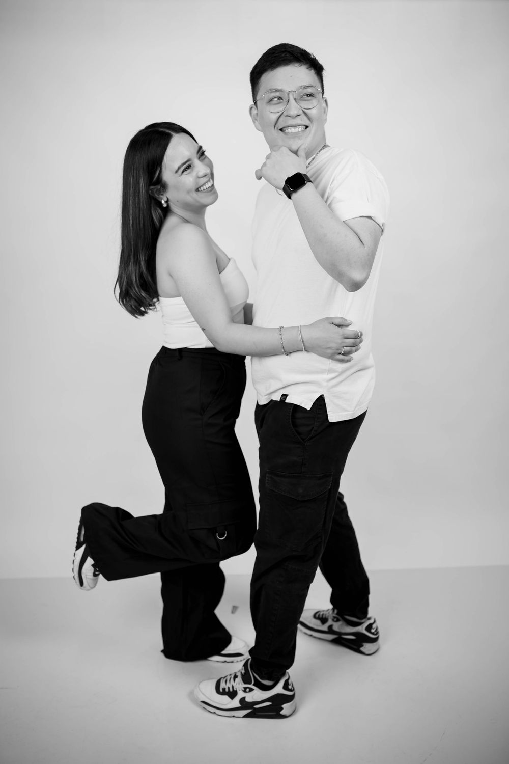 Candid black and white studio photo of a couple in coordinated casual outfits.