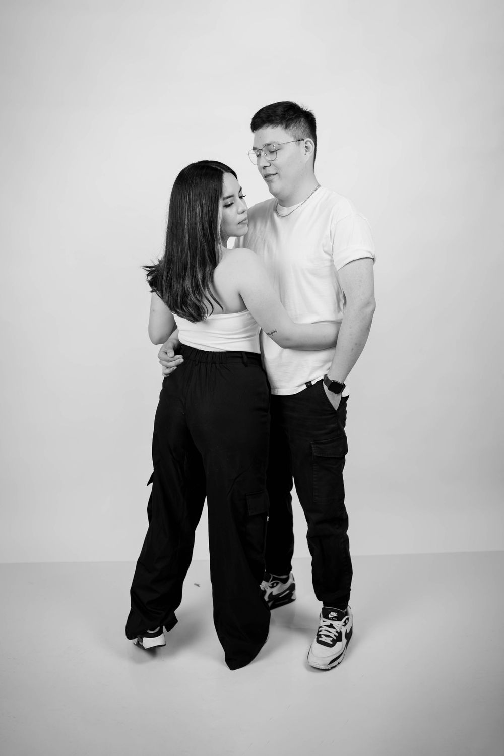 Contemporary black and white portrait of a couple in casual wear standing close together.