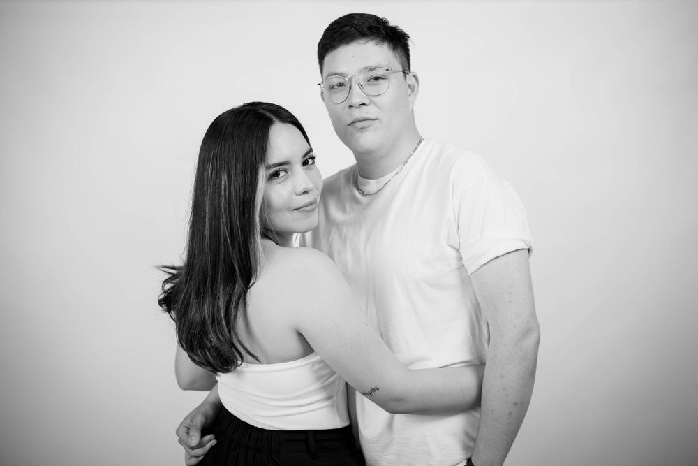 Intimate black and white studio portrait of a couple in contrasting white and black outfits.