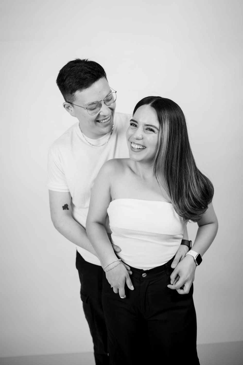 Joyful black and white portrait of a couple laughing together in a studio setting.