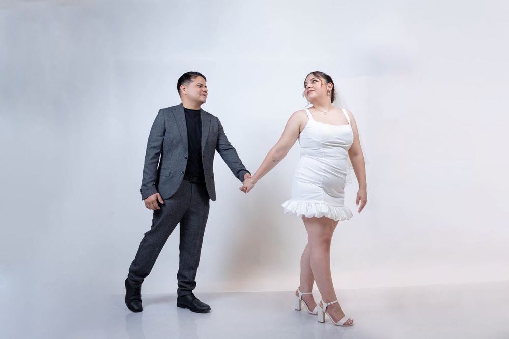 Dancing couple in formal wear against light background, showing movement and joy.