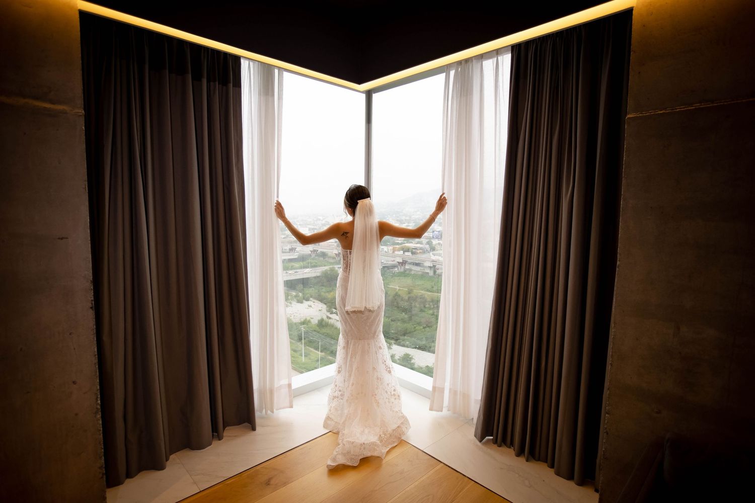 Silhouette against floor-to-ceiling windows with dramatic lighting and curtains.