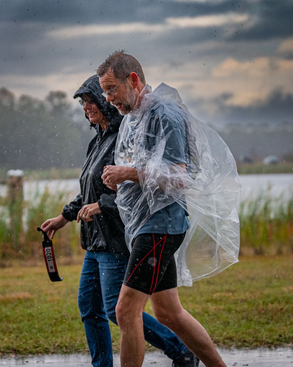 Runners navigating through rain while wearing protective gear during an outdoor event.