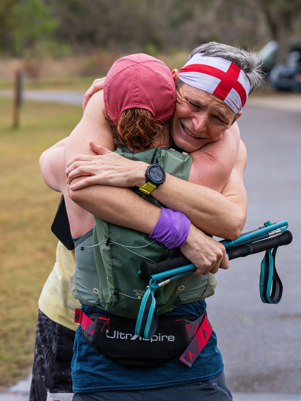 Two athletes sharing an emotional embrace during an outdoor running event.