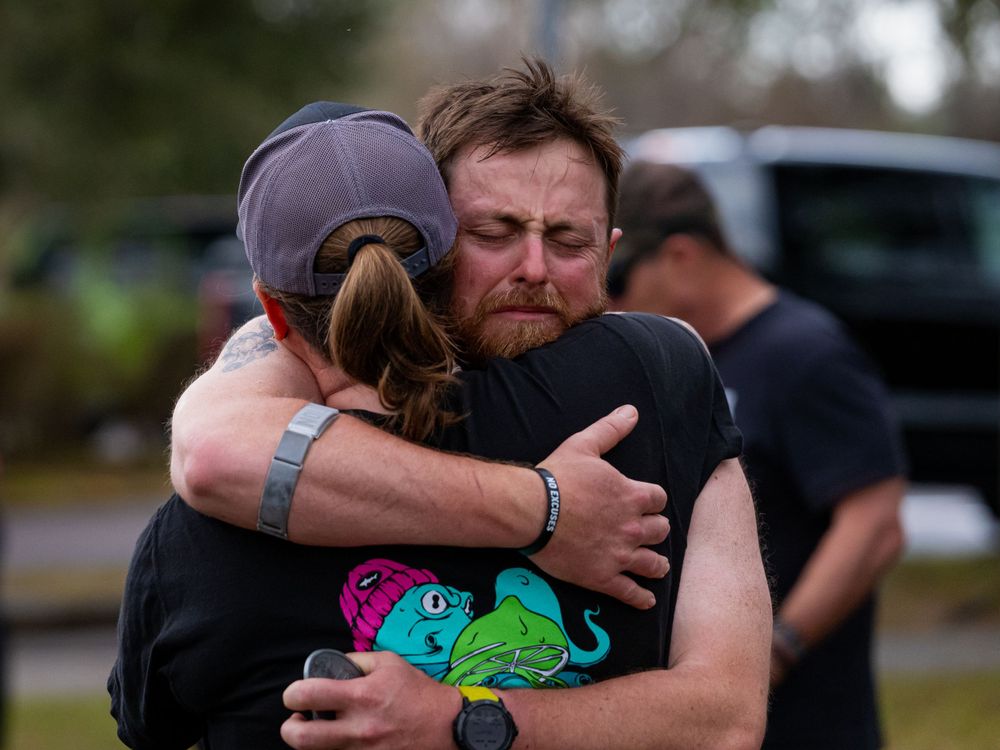 Two runners share an emotional embrace at what appears to be a race finish line.