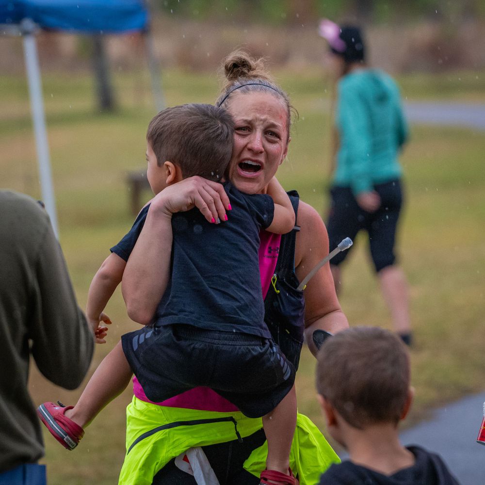Runners celebrating with hugs and joy at an outdoor sporting event.