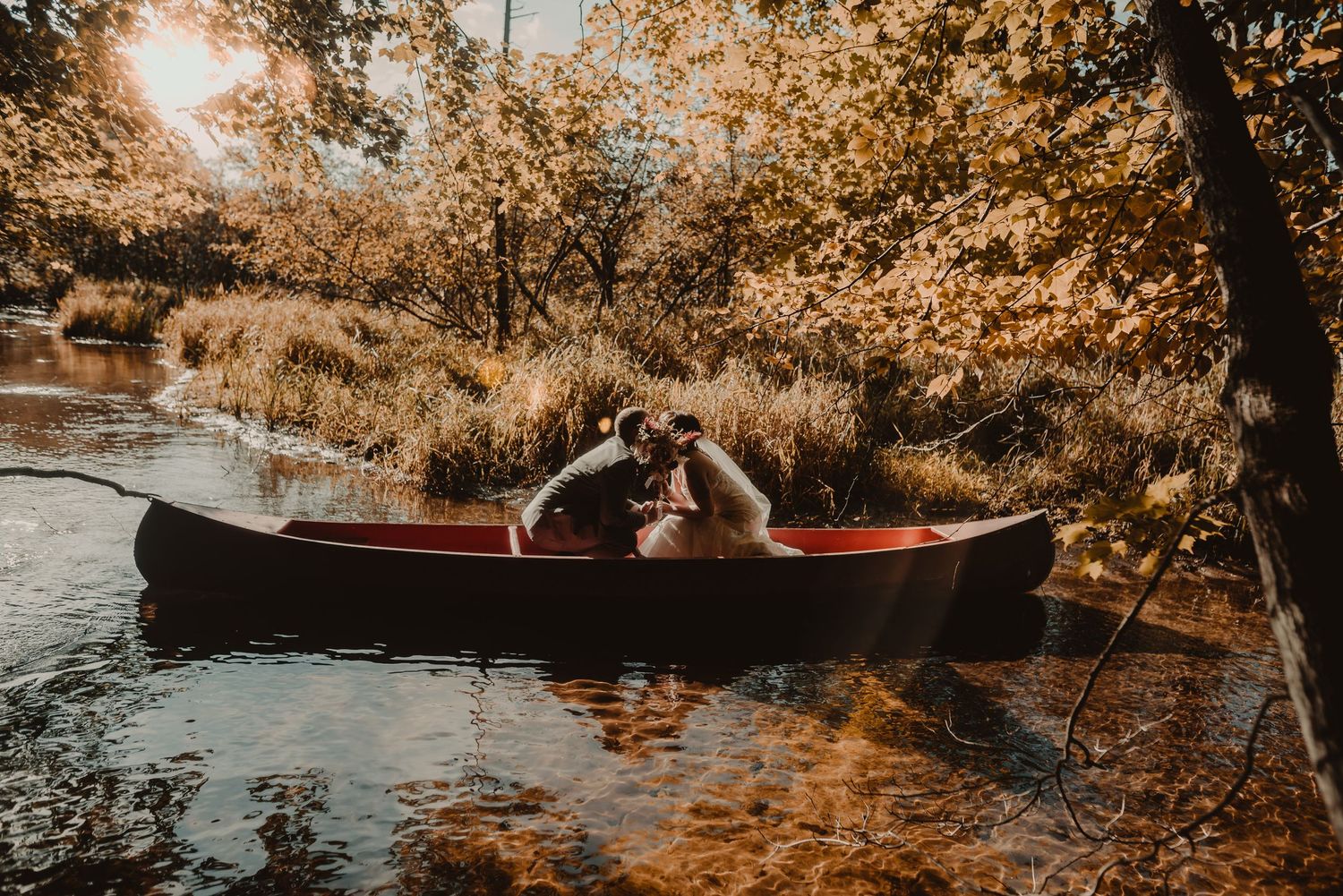 A romantic canoe ride through autumn foliage with golden sunlight reflecting on calm waters.