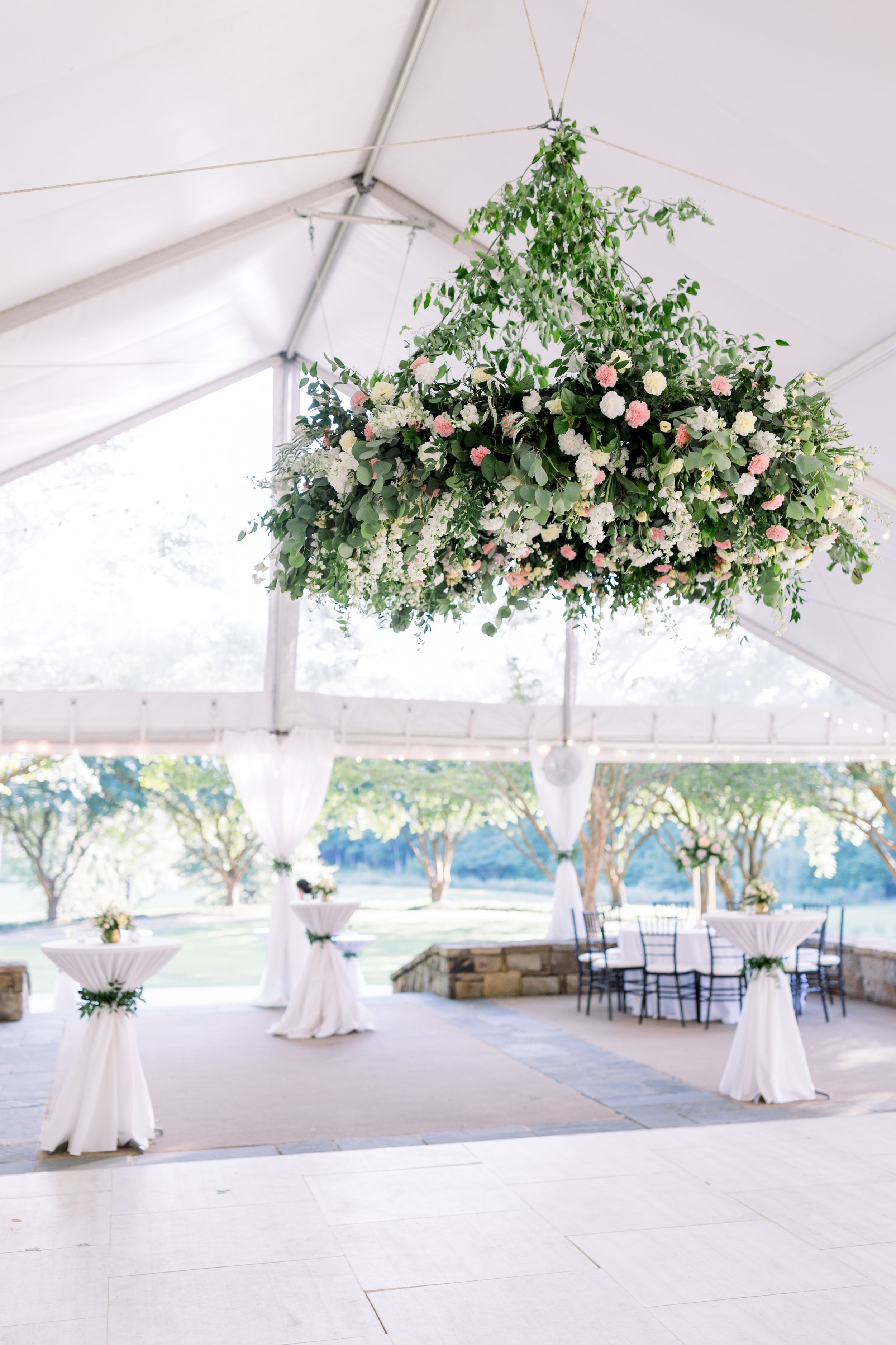 Elegant white wedding tent decorated with floral chandeliers and romantic lighting.