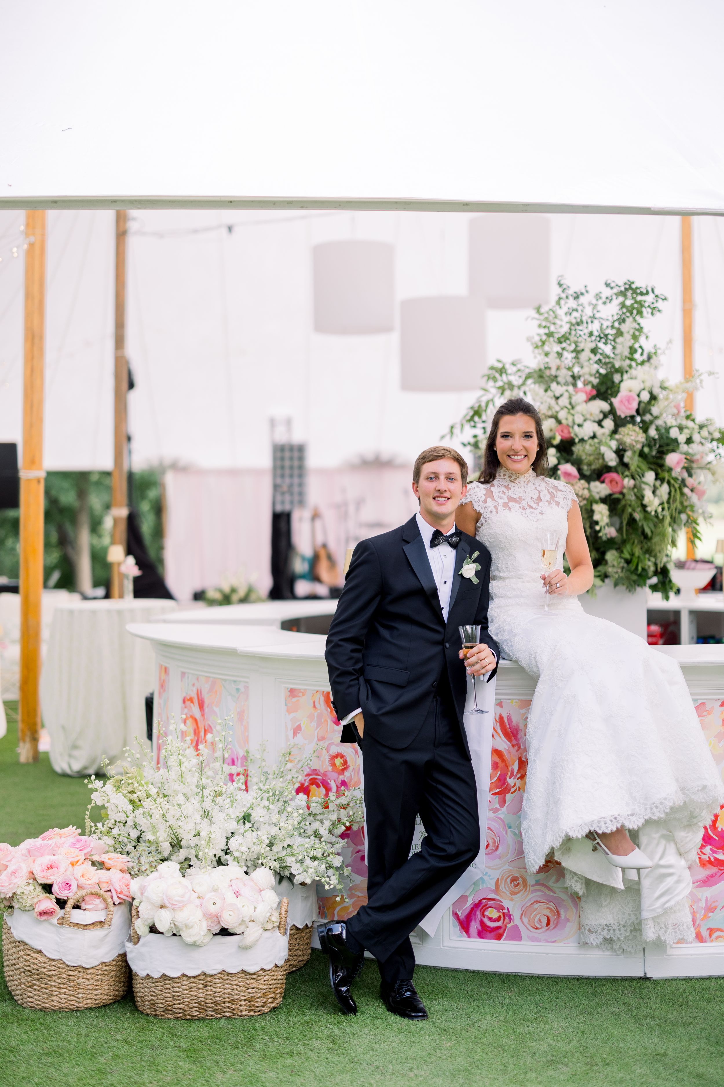 Wedding decor setup featuring pink floral arrangements and elegant white furniture under a tent.