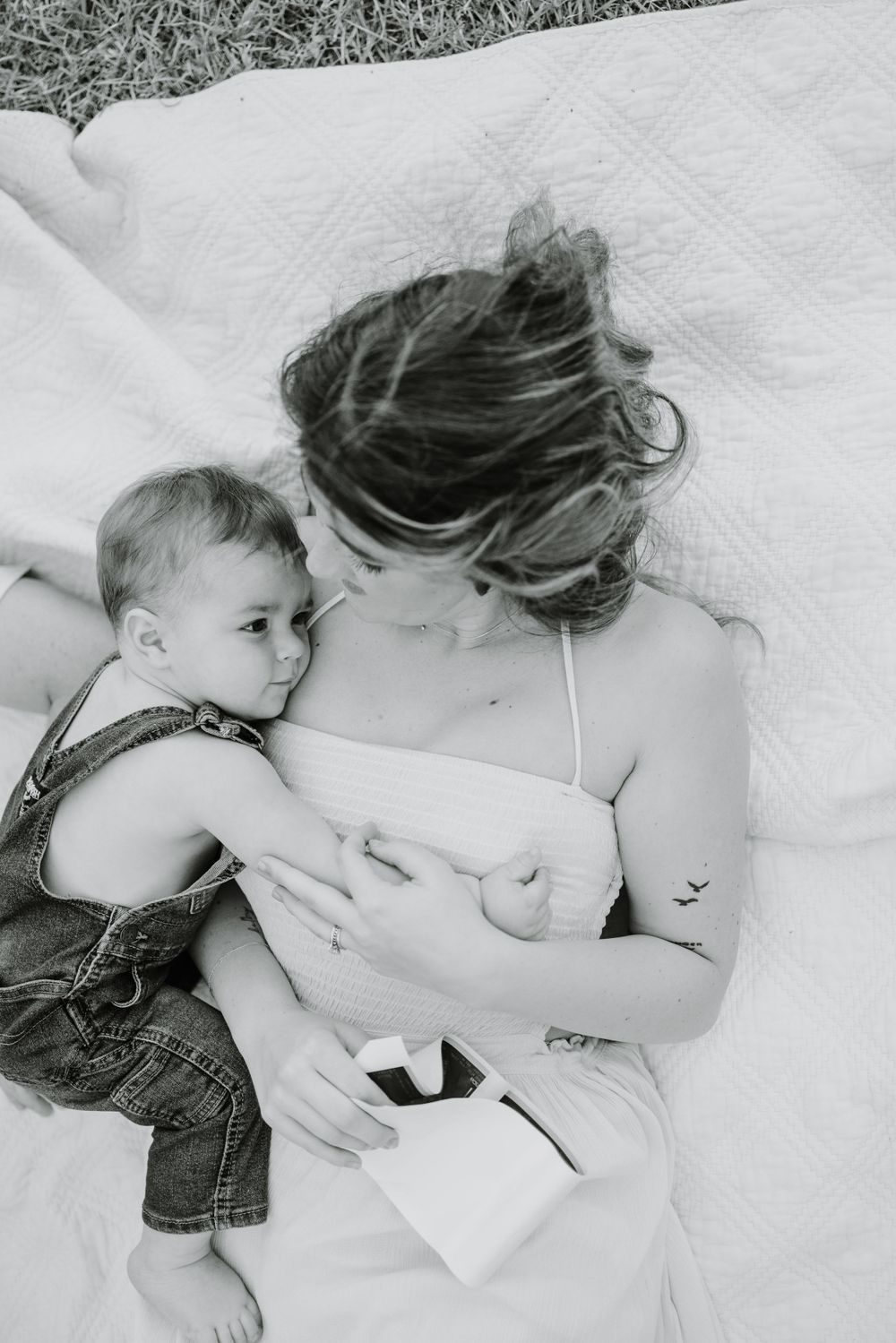 Intimate black and white portraits on a white blanket showing tender family moments.