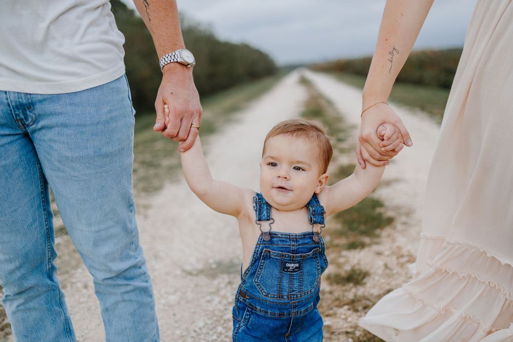Close-up details of casual denim outfits and bare feet during an outdoor family session.