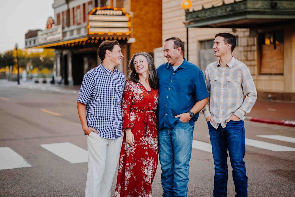 Family walking together on a brick-lined street during golden hour wearing coordinated outfits.