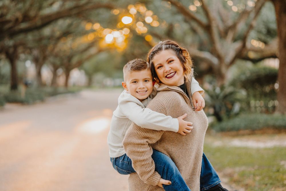 Warm sunset family photos with natural embraces under tree branches with golden bokeh.
