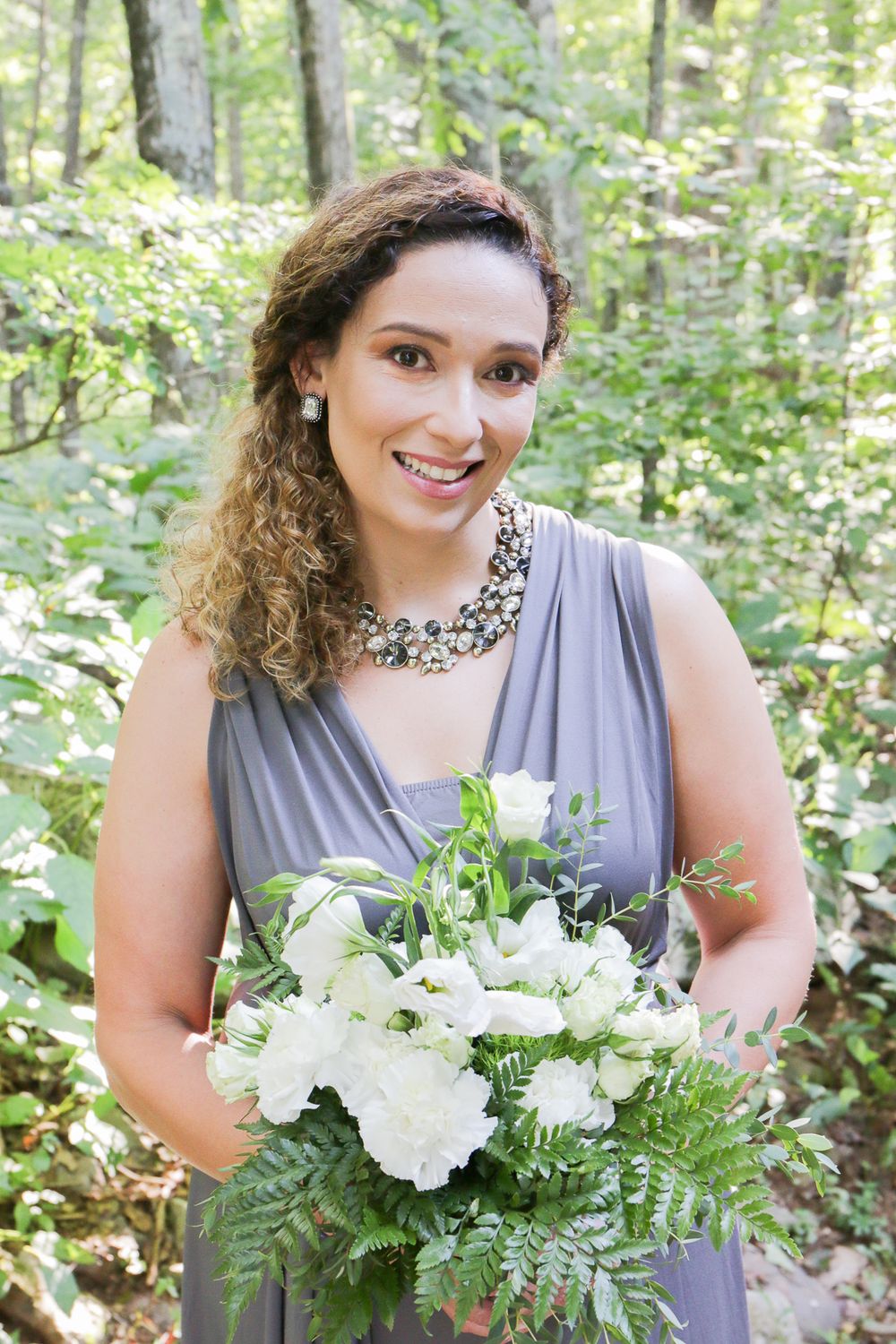 Candid moments with a white and green bouquet against a woodland backdrop.