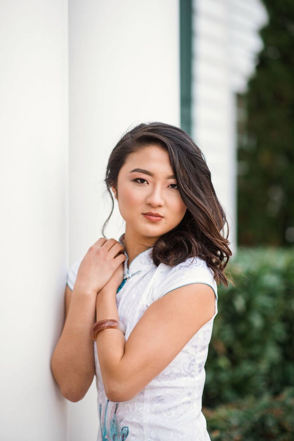 Elegant outdoor portraits in white dress against white columns and greenery.