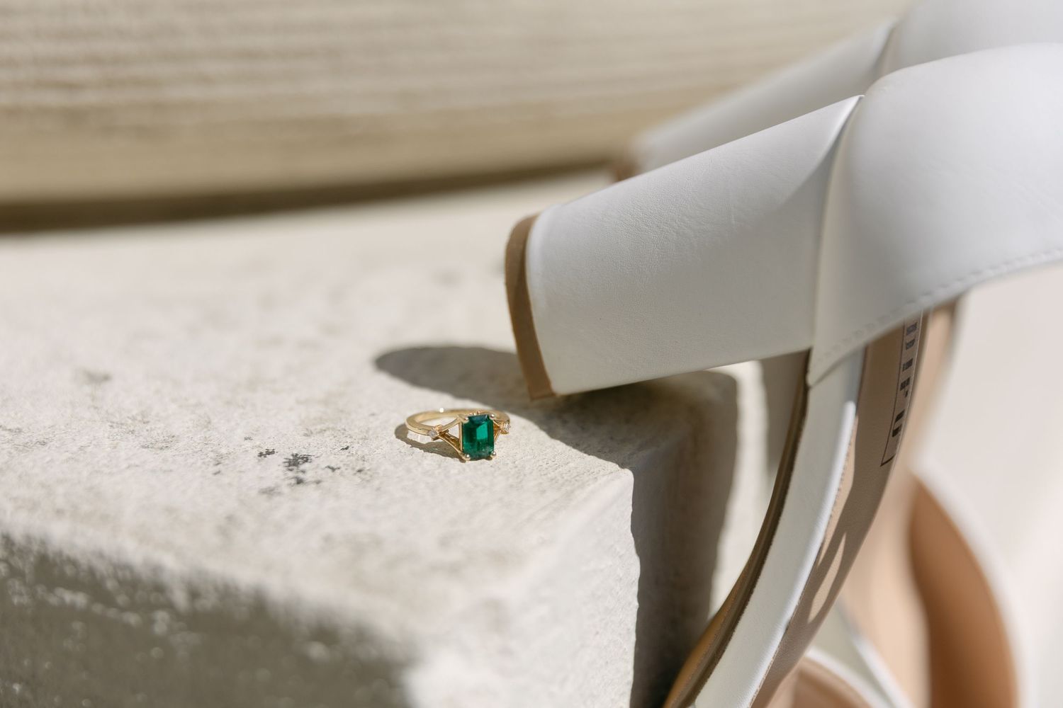 A close-up of hands with an emerald engagement ring resting on fabric, Wadesboro NC Engagement
