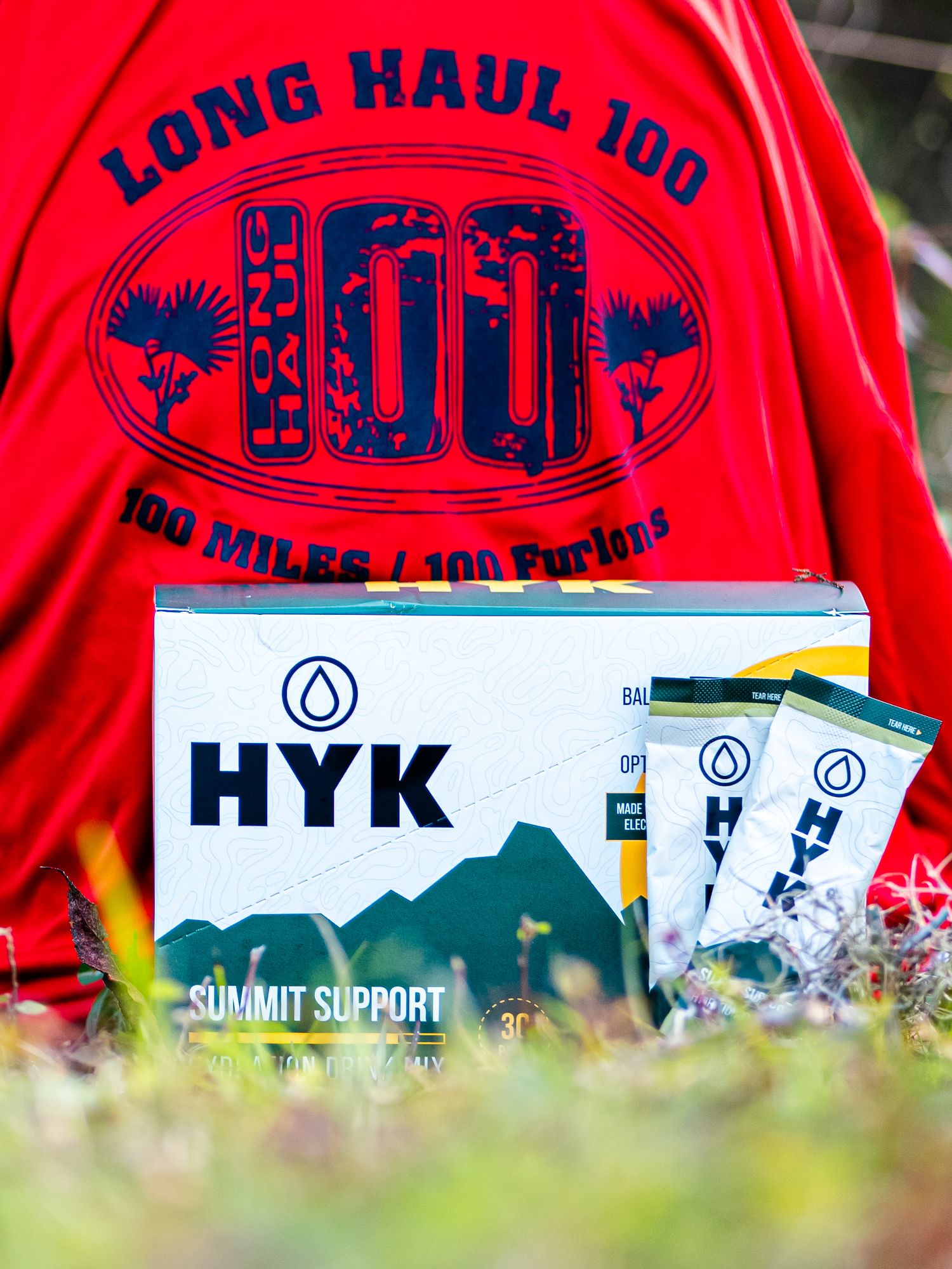 Long Haul 100 ultramarathon shirt and HYK Summit Support products displayed on grass.