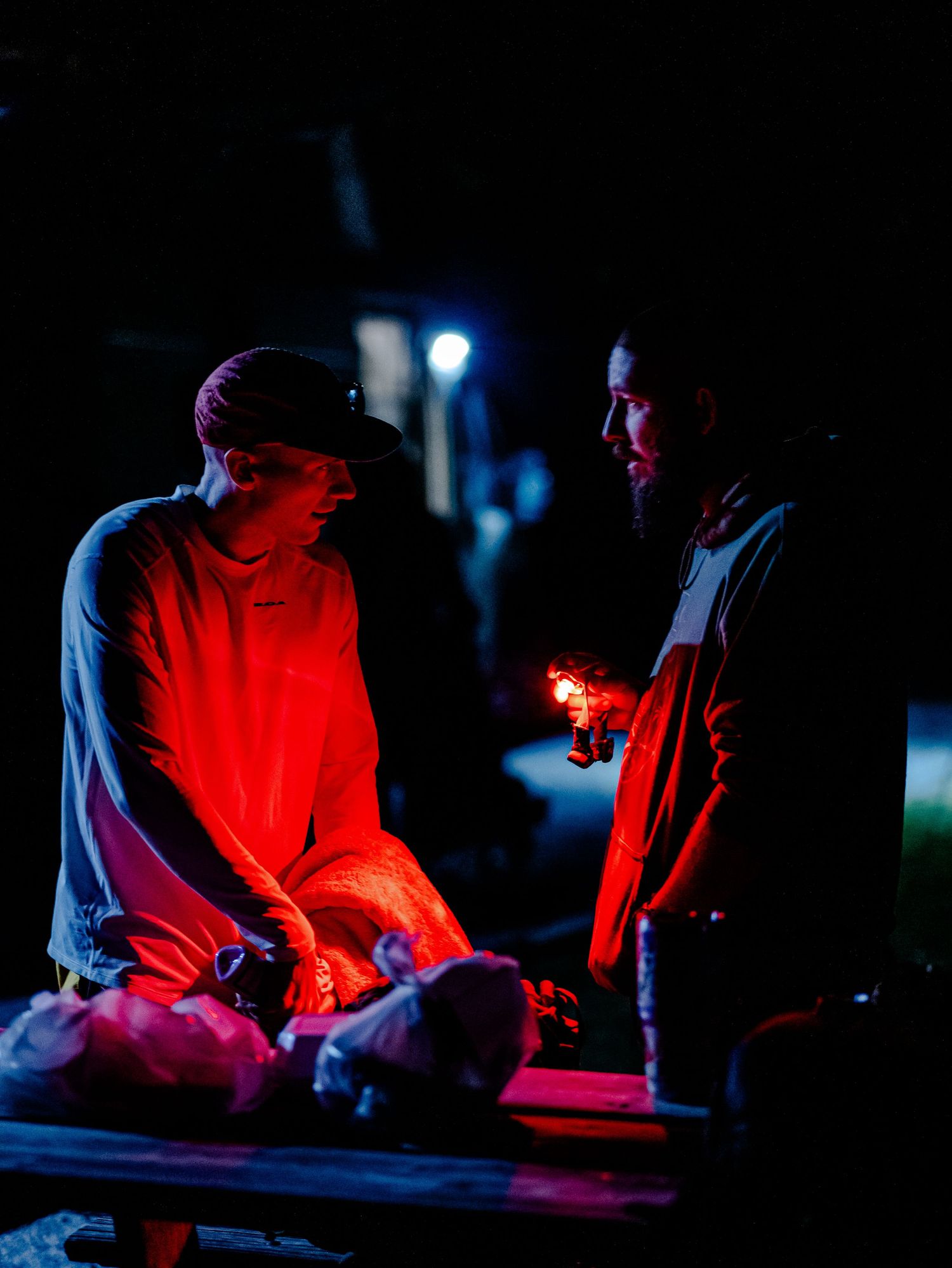 Runners illuminated by red light during nighttime aid station stop.