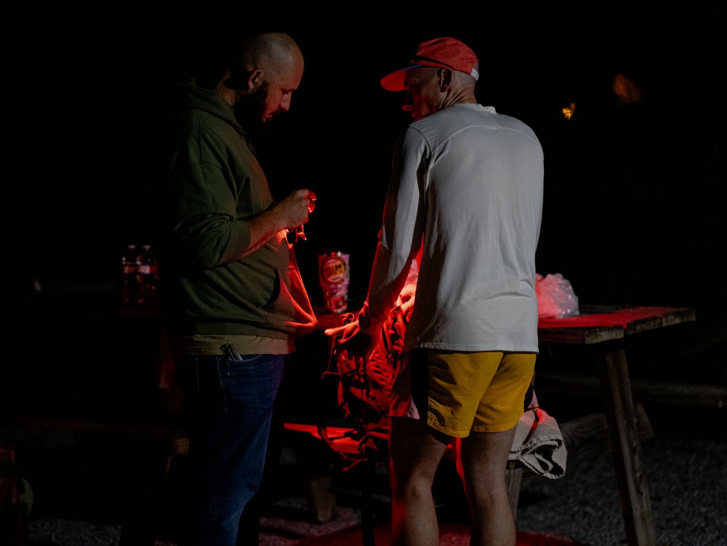 Runners gathered around red glow sticks at nighttime trail race checkpoint.