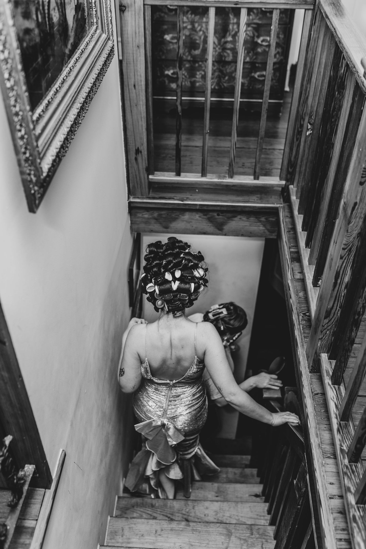 Person in a sparkly silver dress descending vintage wooden stairs.