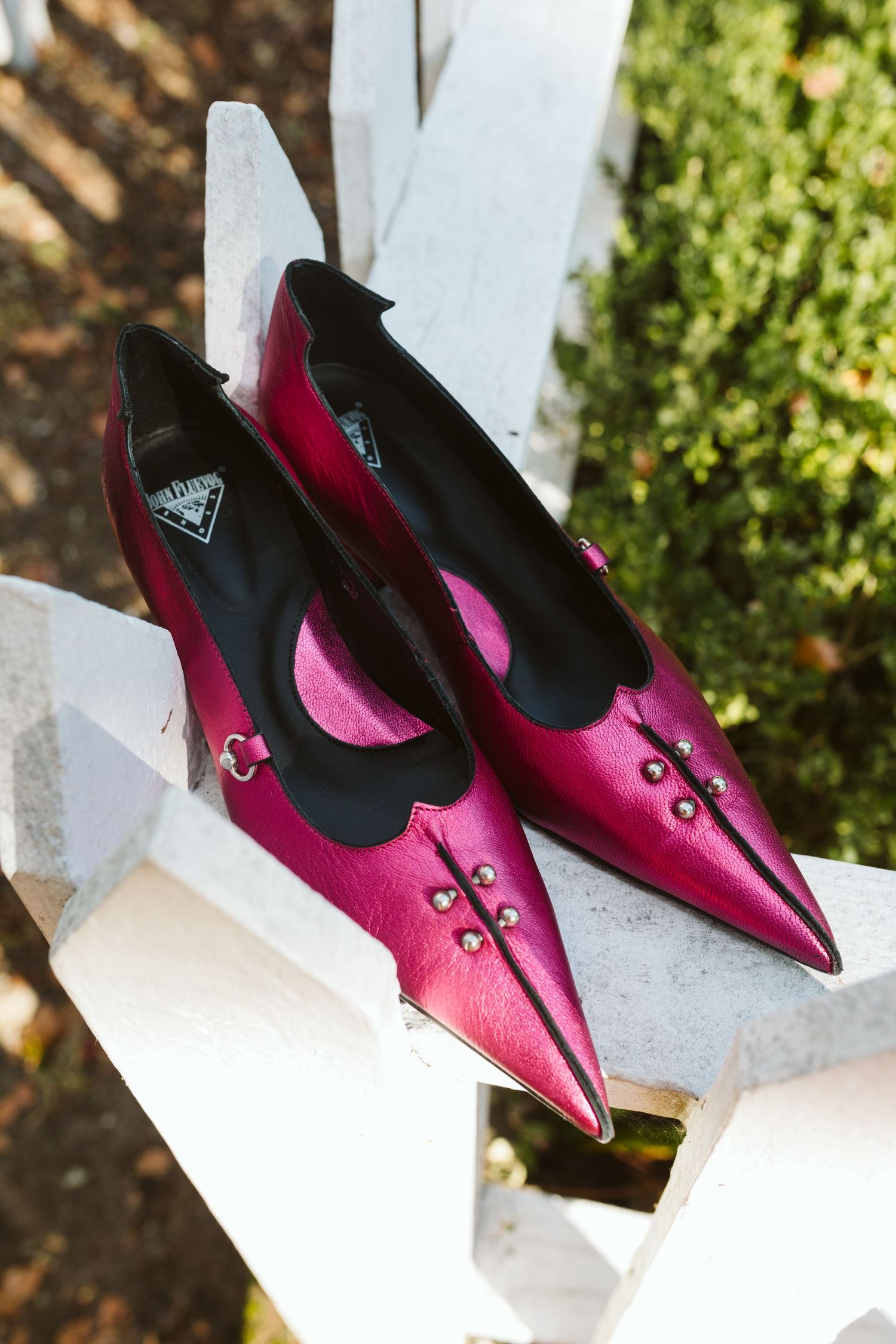 Hot pink pointed-toe dress shoes displayed on white steps outdoors.