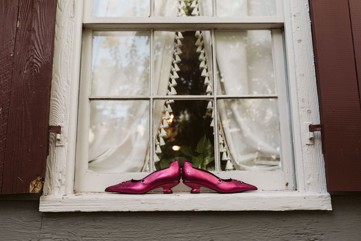 Pink bridal shoes displayed on a rustic windowsill with natural light streaming in.