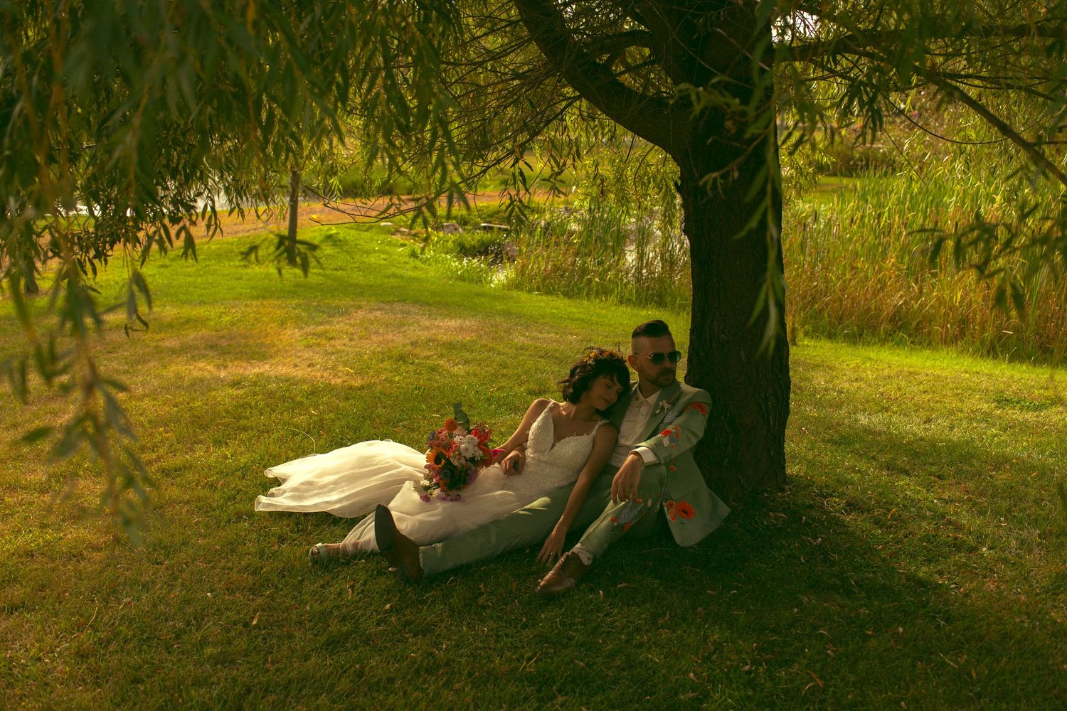 Outdoor wedding ceremony setup with white chairs and floral barrel arrangements along the aisle.