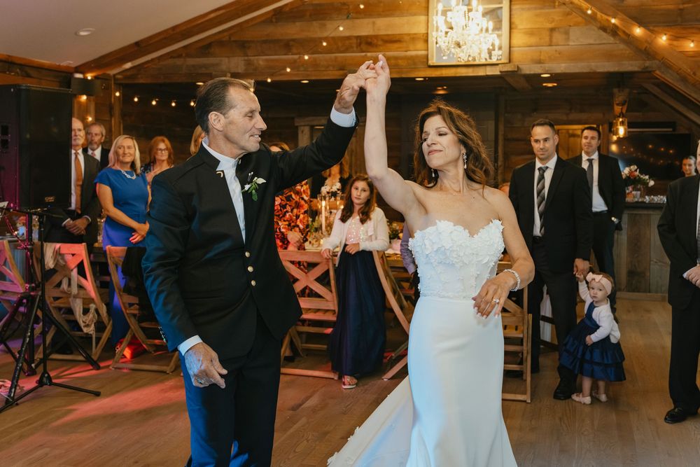 Elegant wedding celebration in a rustic barn venue with string lights and chandelier decorations.